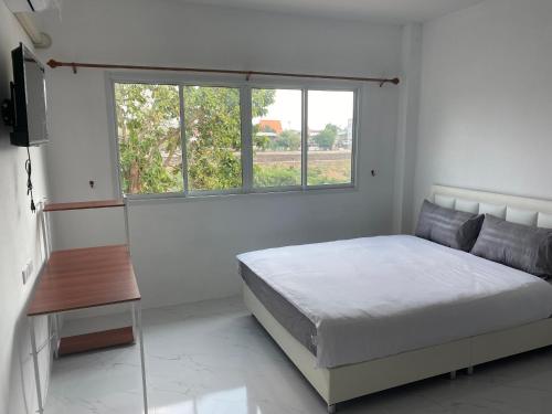 um quarto branco com uma cama e uma janela em จอมเมือง Motel em Nan