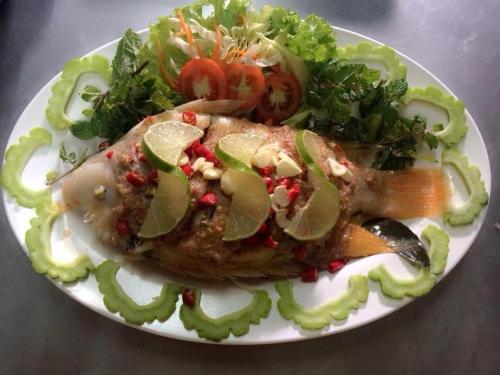 a plate of food with a piece of fish and vegetables at จอมเมือง Motel in Nan