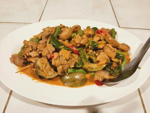 a plate of food on a table with a spoon at จอมเมือง Motel in Nan