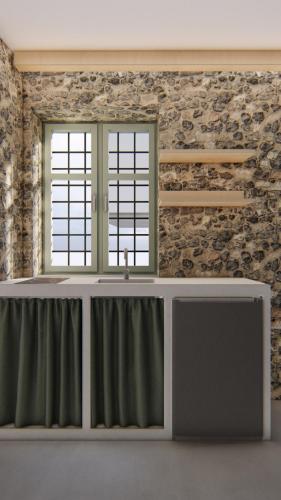 Cette chambre est dotée d'un mur en pierre avec un lavabo et une fenêtre. dans l'établissement Capella Poulia's Home, Skiathos, à Skiathos Chora