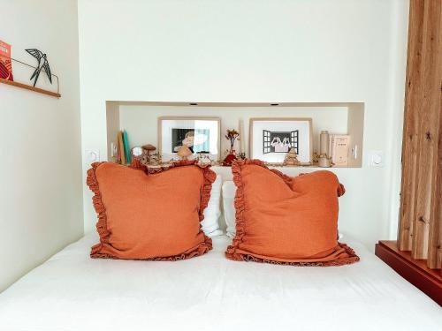- 2 oreillers orange assis sur un lit dans la chambre dans l'établissement Gite à la campagne à Dijon avec jardin, à Velars-sur-Ouche