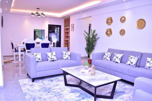 ein Wohnzimmer mit blauen Sofas und einem Tisch in der Unterkunft El ma Furnished Apartment in Nairobi