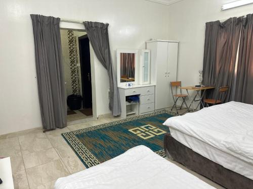 a bedroom with two beds and a desk and a table at Al-Olaya Apartment in Umm Lujj