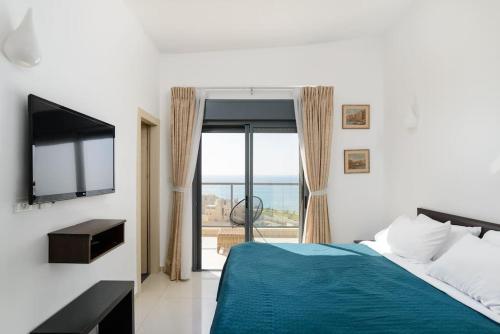a bedroom with a bed and a tv and a window at Jacuzzi Penthouse with wide Sea View in Natanya in Netanya