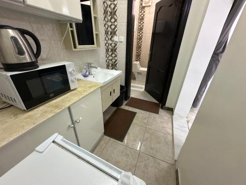 a small bathroom with a sink and a microwave at Al-Olaya Apartment in Umm Lujj