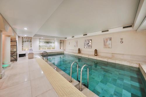 a large swimming pool with green water in a building at Mamaison Le Regina Boutique Hotel in Warsaw
