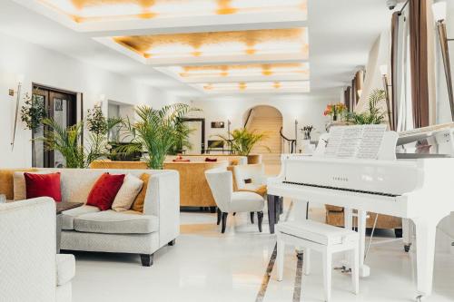 a white piano in a living room with furniture at Mamaison Le Regina Boutique Hotel in Warsaw