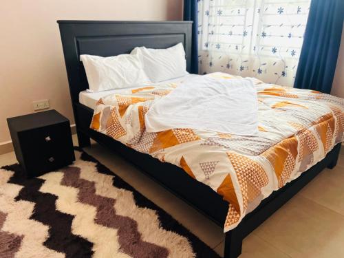 a bedroom with a bed with a black frame at Oaklands Apartments in Morogoro