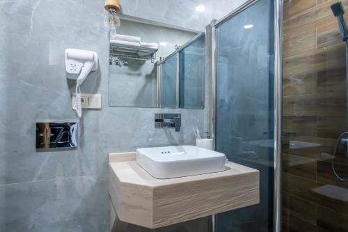 a bathroom with a white sink and a shower at Metekhi Boutique Hotel in Tbilisi City