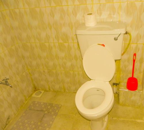 a small bathroom with a toilet with a red brush at Jack Haven Bnb in Kitengela 