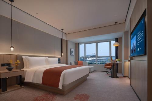 Habitación de hotel con cama grande y TV de pantalla plana. en Howard Johnson Airport Serviced Residence Changsha, en Changsha
