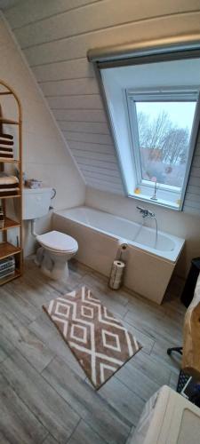 a bathroom with a tub and a toilet and a window at Sonja gemütliche Ferienwohnung in Bruchhausen-Vilsen