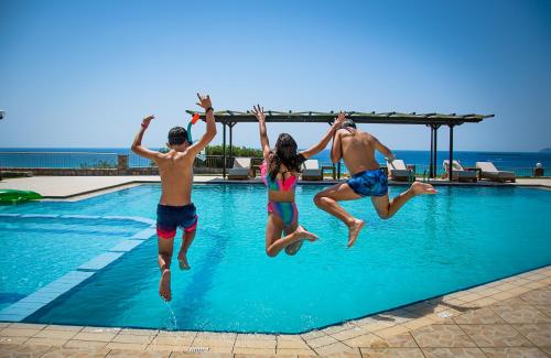 a group of people jumping into a swimming pool at Panorama Hotel in Falasarna