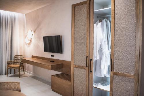 a room with a closet with a tv and a desk at Panorama Hotel in Falasarna