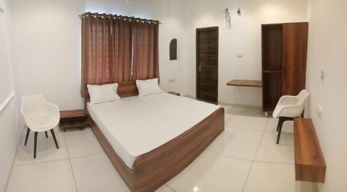 a bedroom with a large bed and chairs in it at Vaatsaly Rooms in Indore