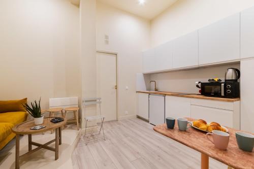 eine Küche und ein Wohnzimmer mit einem Sofa und einem Tisch in der Unterkunft Charmant appartement moderne haut marais - 4P in Paris