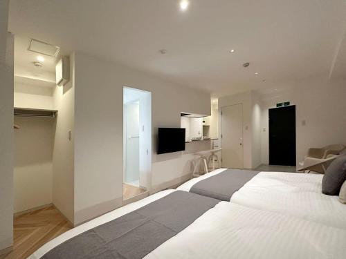 a white bedroom with a large bed and a tv at b hotel Rijodori - City Central Studio Stay with Breakfast in Hiroshima