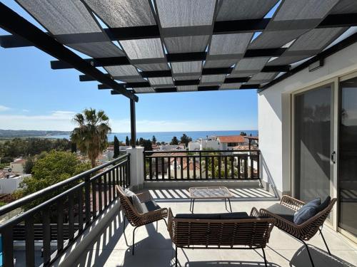 Un patio con sillas y una mesa en el balcón. en Villa Marina Sea-View Private Pool en Peyia