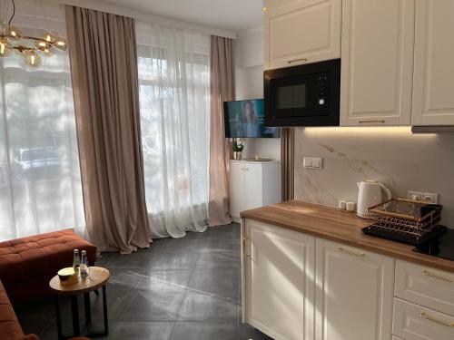 a kitchen with white cabinets and a living room at APARTAMENT AMORE-blisko morza in Międzyzdroje