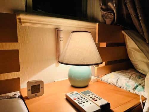 a lamp sitting on a table next to a remote control at Guest room Kurume in Miimachi