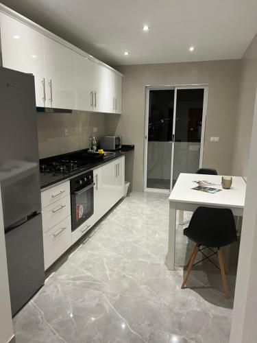 a kitchen with white cabinets and a table and a stove at Brand new apartment in Mindelo in Mindelo