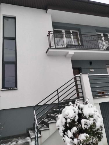 un edificio con balcón y una planta con nieve en Dom jednorodzinny, en Łapy