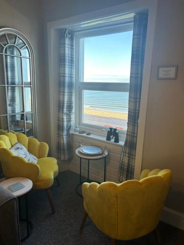 a living room with a yellow chair and a window at Glan Y Mor Hotel (Adult Only) in Llandudno