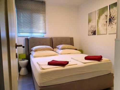 a bed in a bedroom with red pillows on it at 1 Haus Linden Osljak in Island Osljak