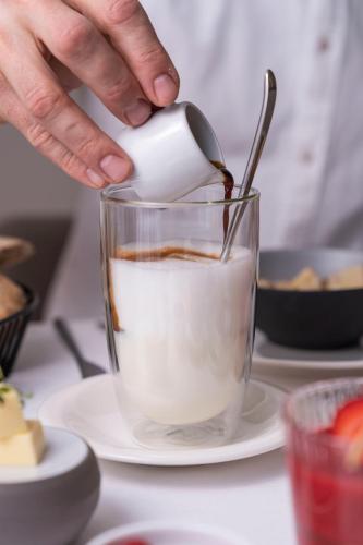 a person pouring milk into a cup of coffee at Zum Hirschen Boutique Hotel Val di Non in Unsere Liebe Frau im Walde