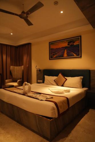 Schlafzimmer mit einem Bett, einem Ventilator und einem Stuhl in der Unterkunft hotel badri palace in Jodhpur
