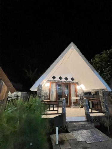 a white tent at night with a table and chairs at Meno Melani guesthouse in Gili Meno