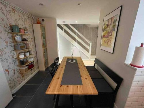 a dining room with a wooden table and a staircase at Milan Casa in Winnersh