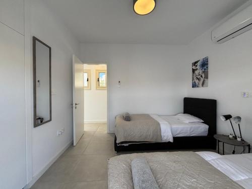 a white bedroom with a bed and a mirror at Villa Marina Sea-View Private Pool in Peyia