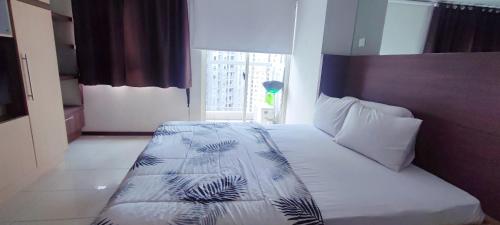 a bedroom with a bed with white sheets and a window at Royal Deluxe & Private Apartments - West Jakarta in Jakarta