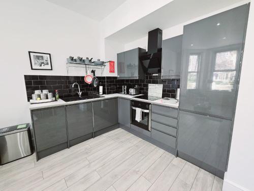 a kitchen with stainless steel appliances and black and white tiles at Stylish Apartment in Victorian Conversion FREE PARKING & PRIVATE PATIO Close to Beach Town Centre & BIC in Bournemouth