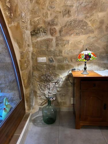 a table with a lamp and a vase with flowers at La Fusteria d' Arnes in Arnés