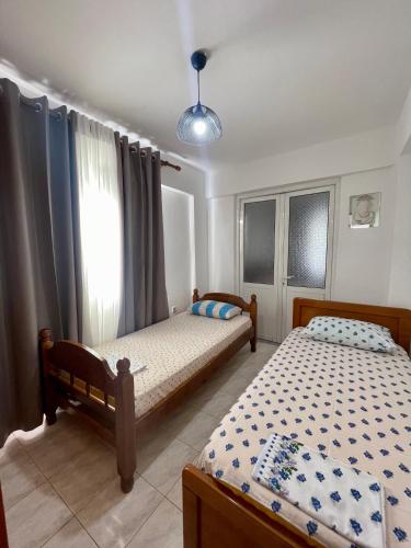 a bedroom with two beds and a window at Guest House Luli in Sarandë