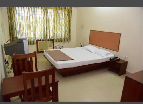 a bedroom with a bed and a table and chairs at HOTEL ROYAL PARK in Mangalore