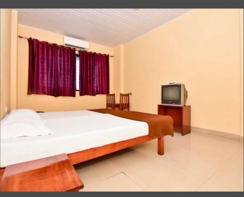 a bedroom with a large bed and a tv at HOTEL ROYAL PARK in Mangalore