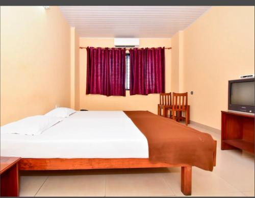 a bedroom with a large bed and a television at HOTEL ROYAL PARK in Mangalore