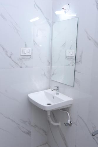 a white bathroom with a sink and a mirror at PRC Residency in Chennai