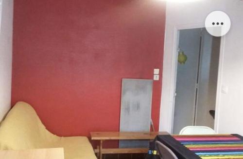 Cette chambre dispose d'un mur rouge, d'une table et de chaises. dans l'établissement Belle chambre dans le quartier latin, à Paris