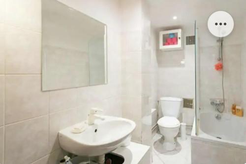 uma casa de banho branca com um lavatório e um WC em Belle chambre dans le quartier latin em Paris