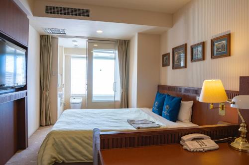 a hotel room with a bed and a telephone at Hotel Boston Plaza Kusatsu in Kusatsu