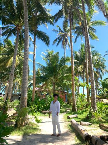 a man standing on a path in front of palm trees at Jaydy hostel in General Luna