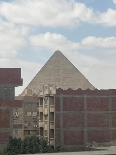 uma pirâmide atrás de um edifício em frente a um edifício em Badr pyramids inn em Cairo