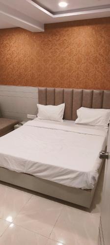 a bed with white sheets and pillows in a room at Hotel tapovan inn in Ahmedabad