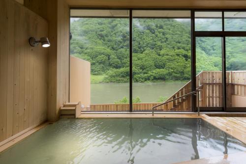 a swimming pool with a view of a river at Takamiya Ryokan Beni in Tozawa