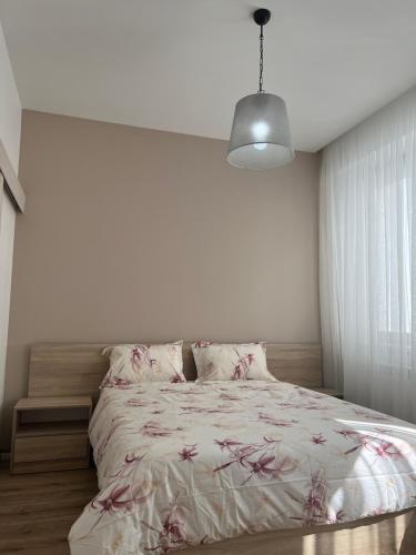 1 dormitorio blanco con 1 cama con sábanas estampadas de flores en Magic Home, en Chişinău