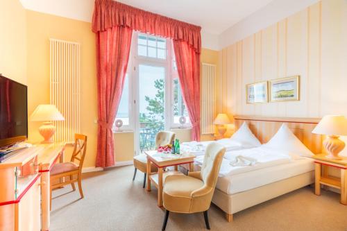 une chambre d'hôtel avec un lit, une table et des chaises dans l'établissement Strandhotel Möwe, à Bansin